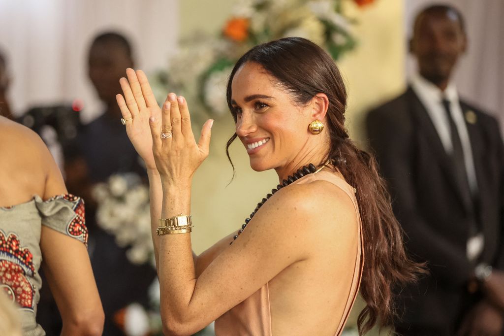 Meghan, Duchess of Sussex, gestures as she arrives with Britain's Prince Harry (unseen), Duke of Sussex, during their visit at the Lightway Academy in Abuja on May 10, 2024 as they visit Nigeria as part of celebrations of Invictus Games anniversary. (Photo by Kola SULAIMON / AFP) (Photo by KOLA SULAIMON/AFP via Getty Images)