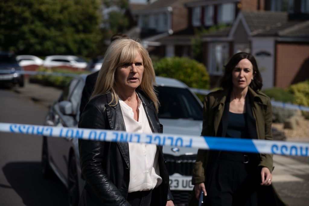 Two women standing behind blue police tape