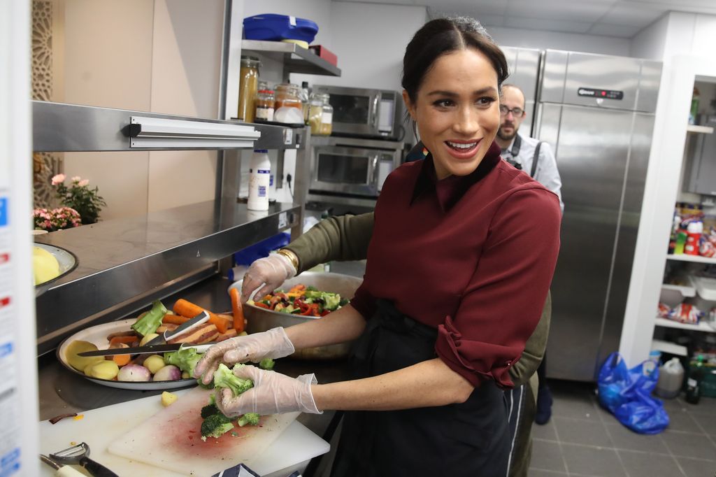 Meghan Markle chopping up food in an industrial kitchen