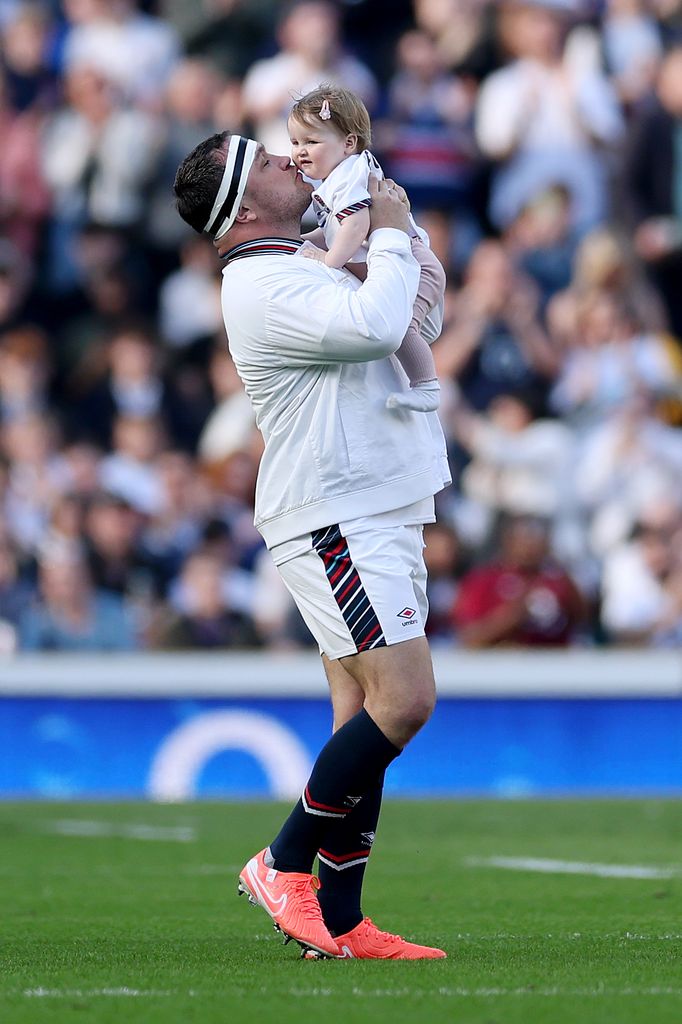 Jamie George carrying and kissing his daughter