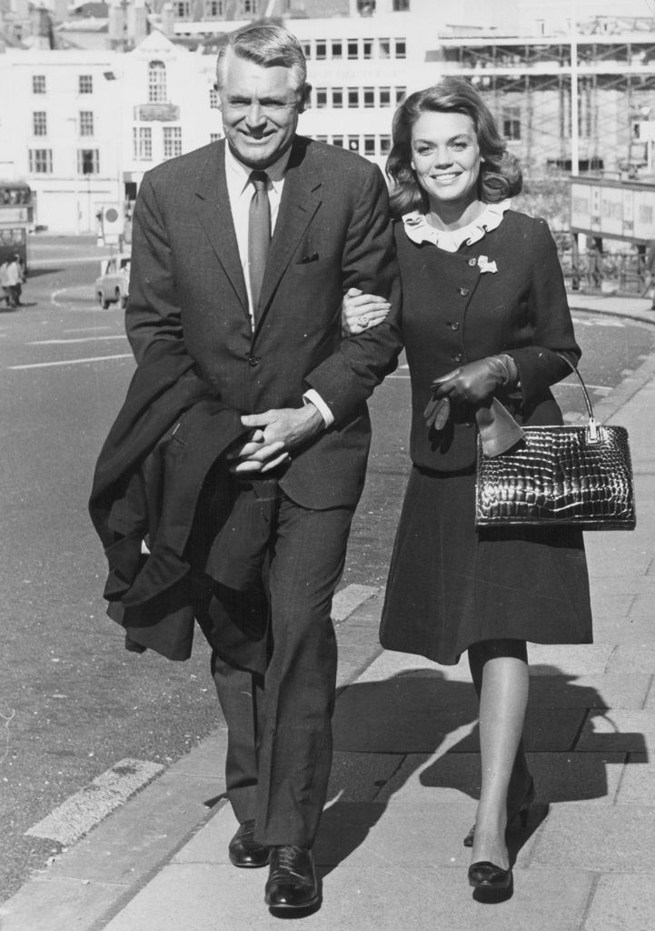 Actor Cary Grant and his wife, actress Dyan Cannon, walking arm in arm down a street in Bristol, England, 1965