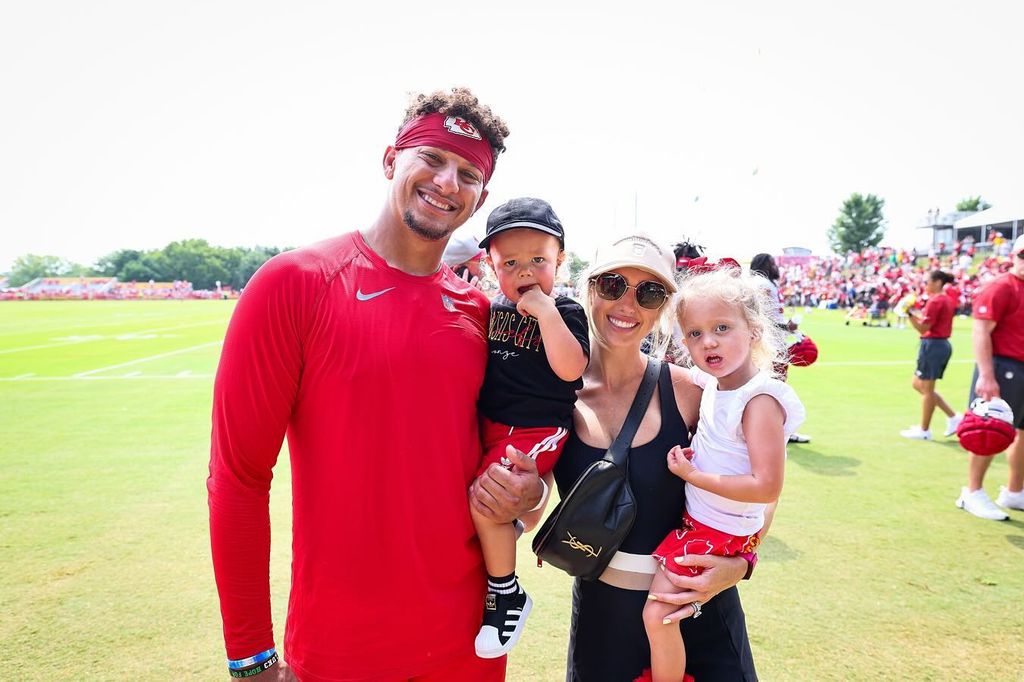 patrick and brittany mahomes with two of their kids on a field