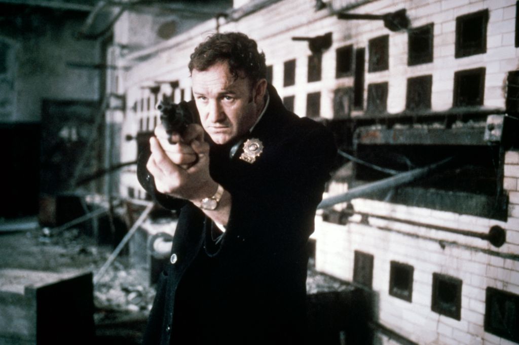 Gene Hackman pointing a gun towards the camera while filming The French Connection