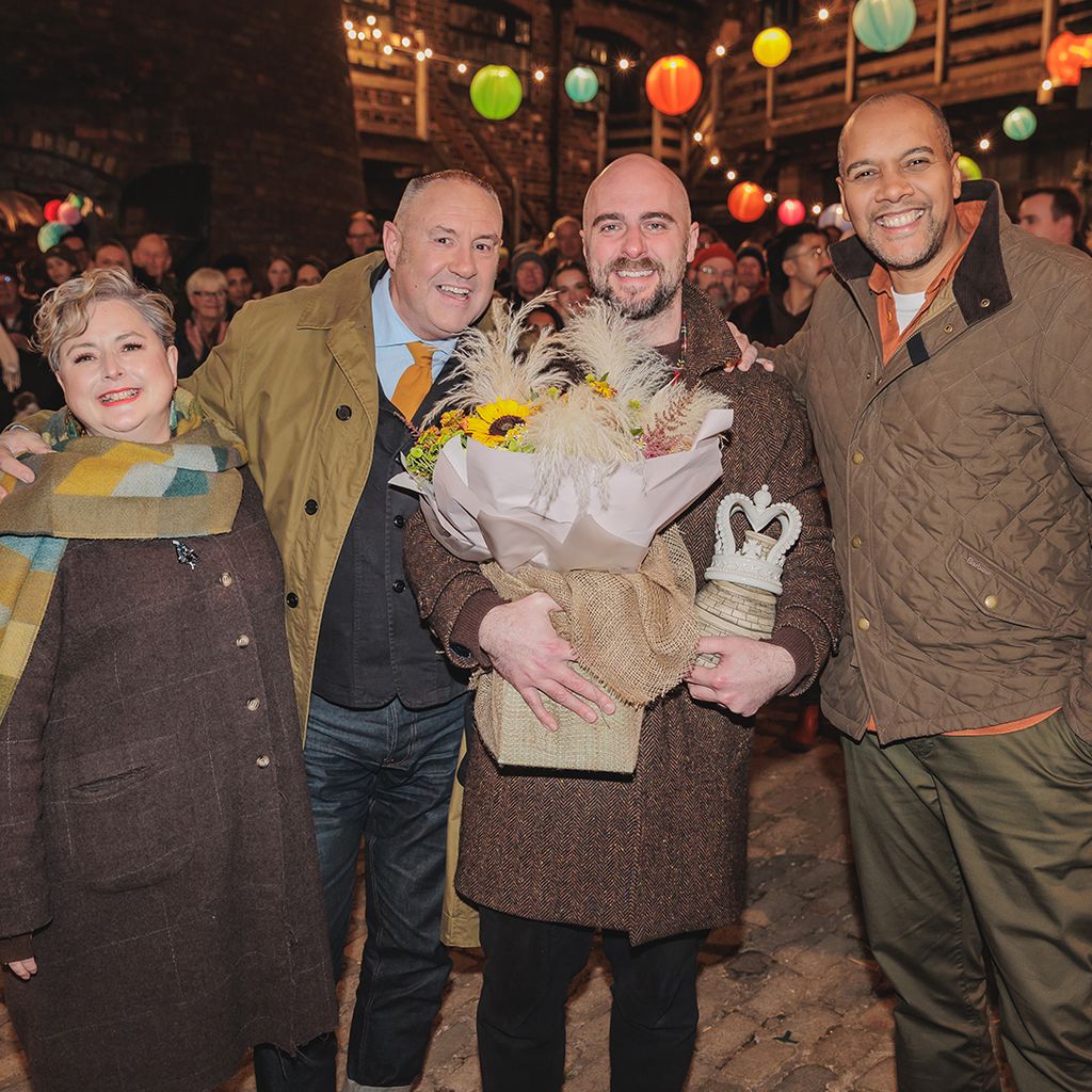 Four people smiling for photo, one man holding flowers