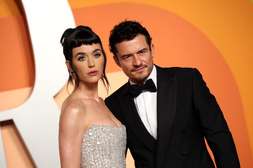 Katy Perry and Orlando Bloom stood side by side wearing formal attire while posing on the red carpet of the Vanity Fair Oscars Party