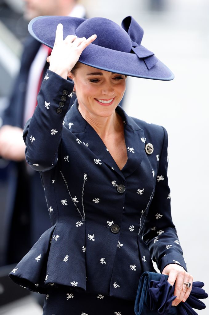 The Princess of Wales holds onto her hat in the wind in navy floral jacket