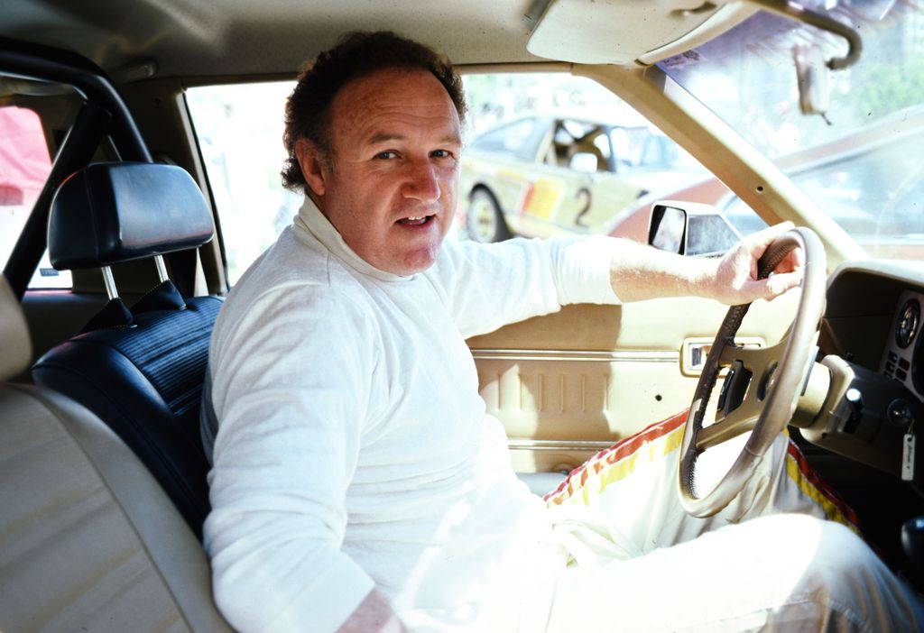 gene hackman sitting in a car looking at camera