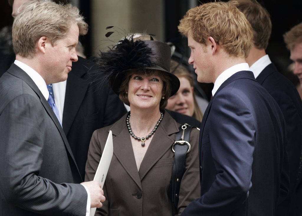 Lady Sarah Spencer in a brown suit and black feathered hat, smiling at Prince Harry who is talking to Earl Spencer