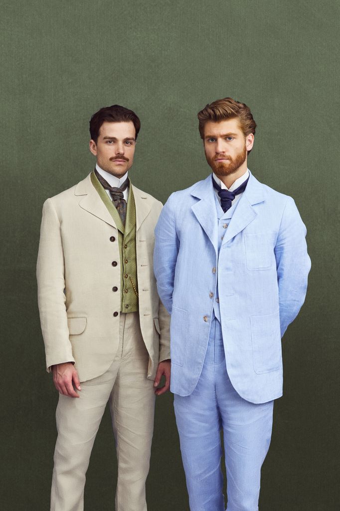 two young men, one in cream suit, one in blue against green background