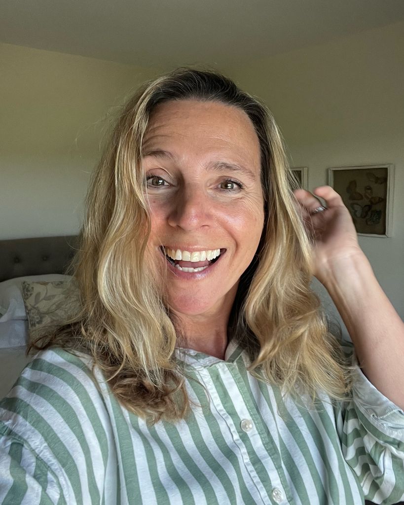 Blonde woman smiling for a selfie in a striped shirt