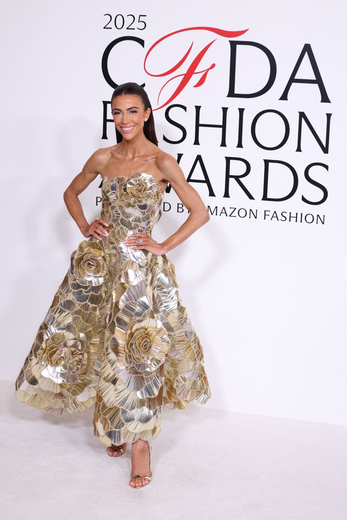 Skye Hankey attends the CFDA 2025 Awards and poses in a gold sequinned gown with her hands on her hips