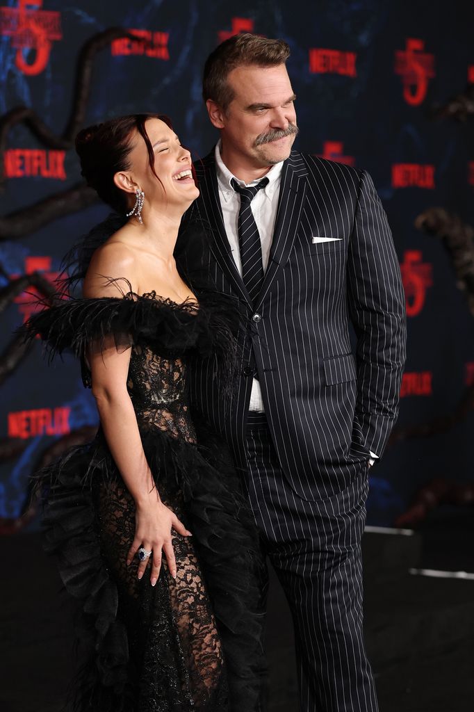A photo of Millie Bobby Brown laughing next to David Harbour