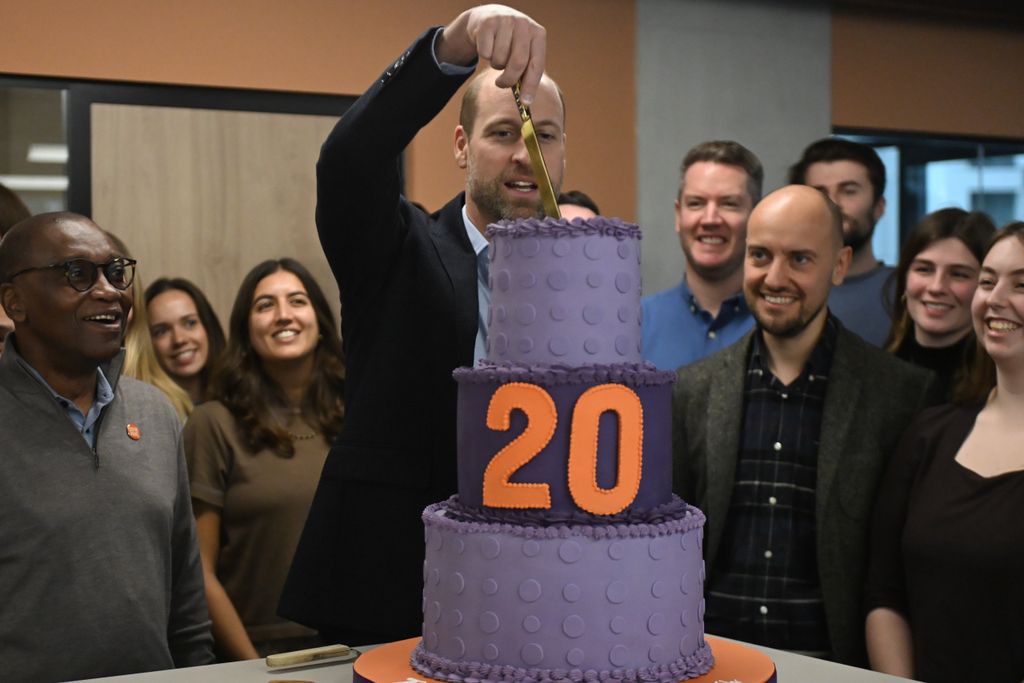 Prince William slicing into a cake with a golden knife