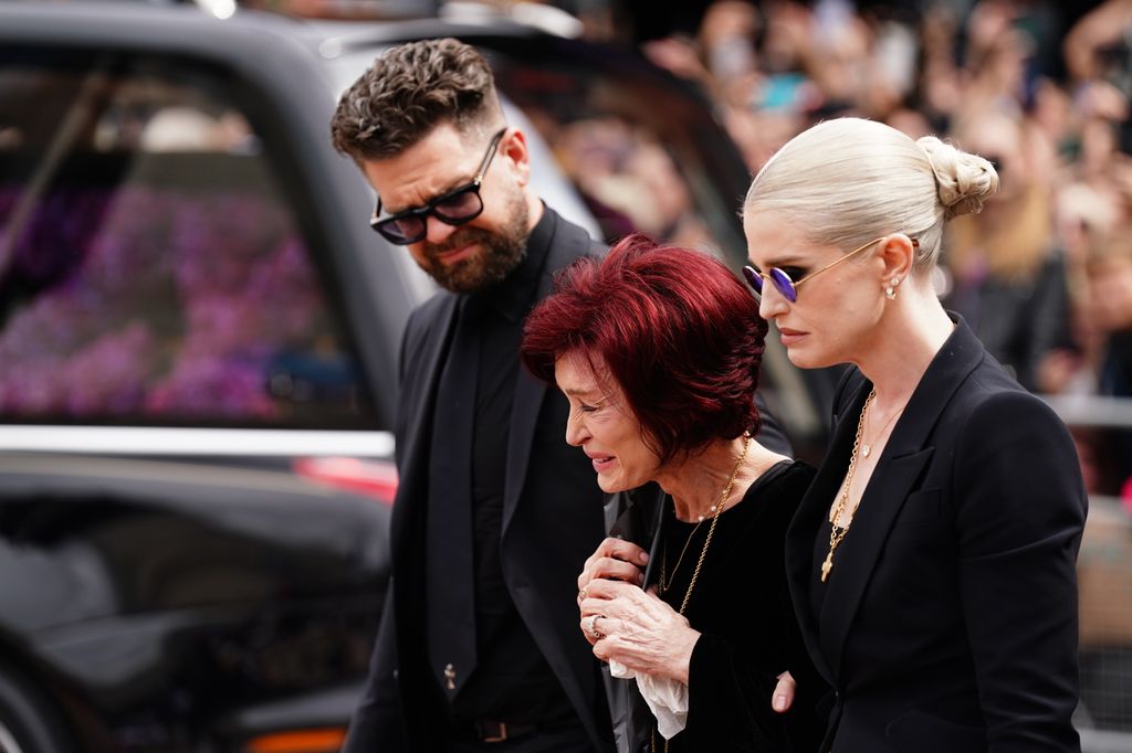 The family of Ozzy Osbourne (left to right) Jack Osbourne, Sharon Osbourne and Kelly Osbourne lay flowers and view the messages and floral tributes left at the Black Sabbath Bridge bench on Broad Street in Birmingham in memory of Black Sabbath frontman Ozzy Osbourne, as his body is brought back to his home city for a procession following his death last week aged 76. Picture date: Wednesday July 30, 2025