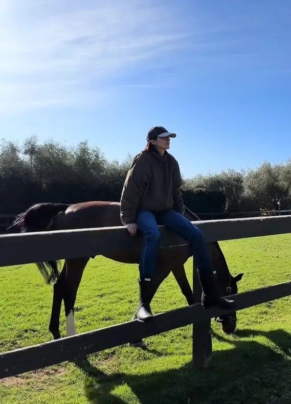photo of kendall jenner sitting on fence by horse at montecito home