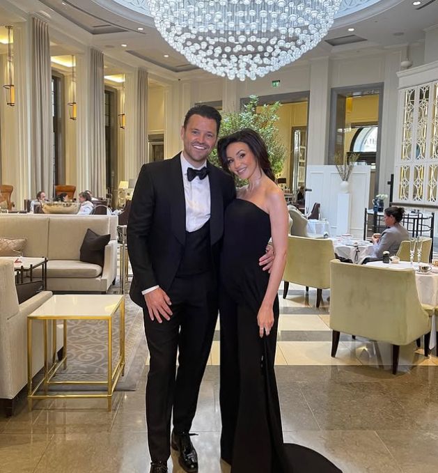 Mark Wright in a black tuxeod with his arm around Michelle Keegan in a black dress