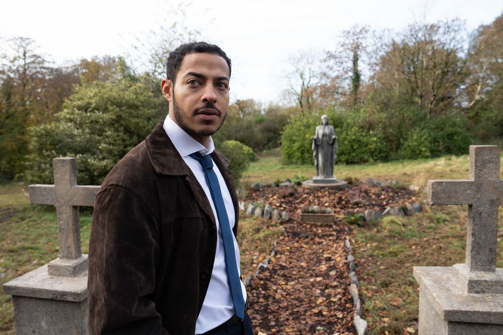 MAN IN SUIT STANDING IN GRAVEYARD