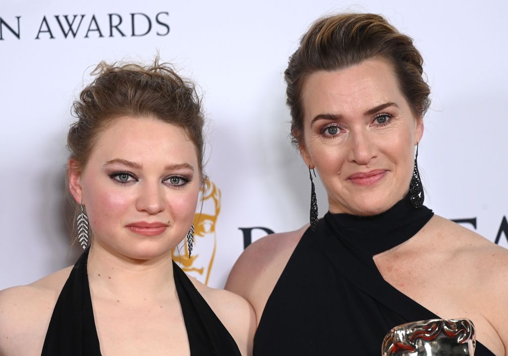 mother and daughter dress in black posing on red carpet