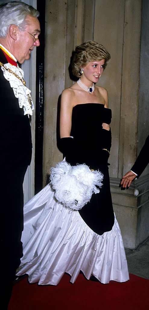 Princess Diana at Mansion House wearing a black strapless dress with white flowing hem and pearl chocker with large blue gem in the middle. 