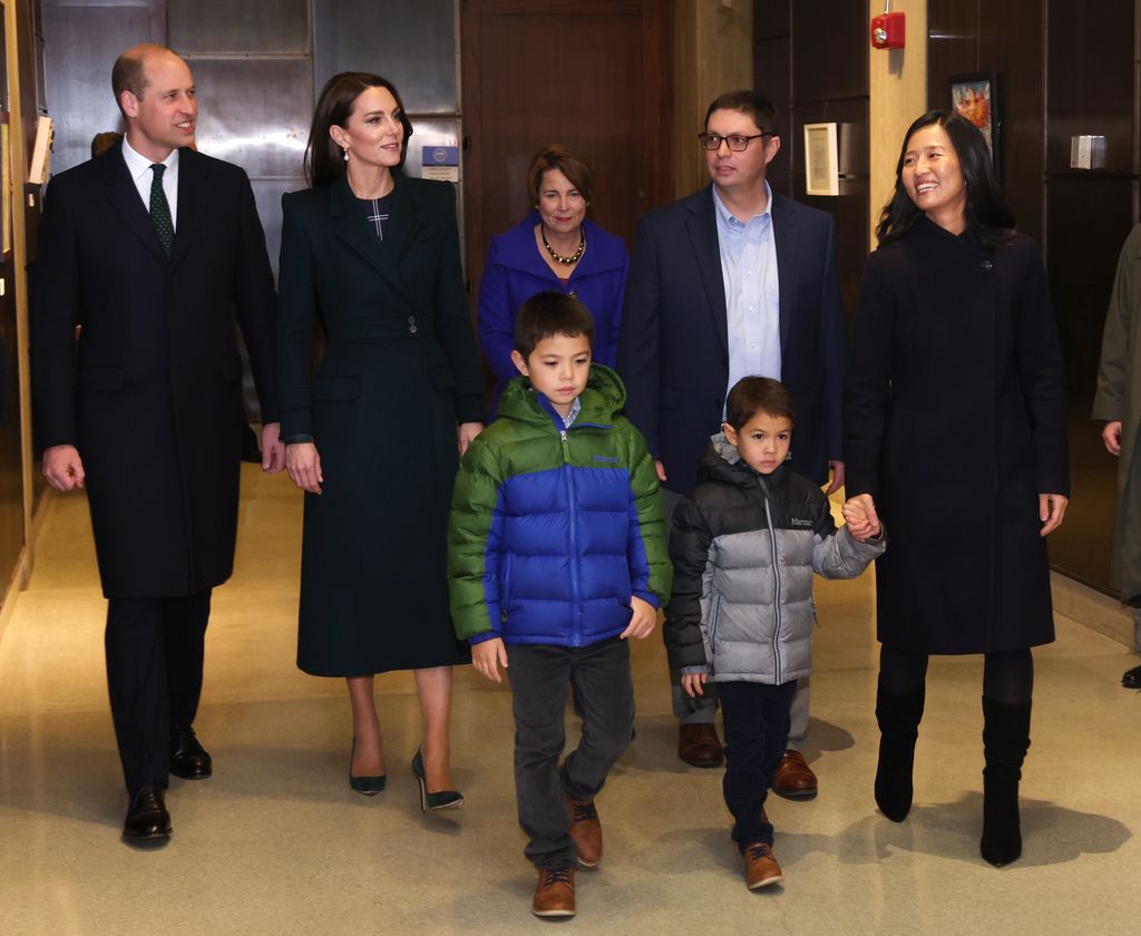 The Prince and princess of Wales walking beside Mayor Michelle Wu and her husband, Conor Pewarski and their children in coats