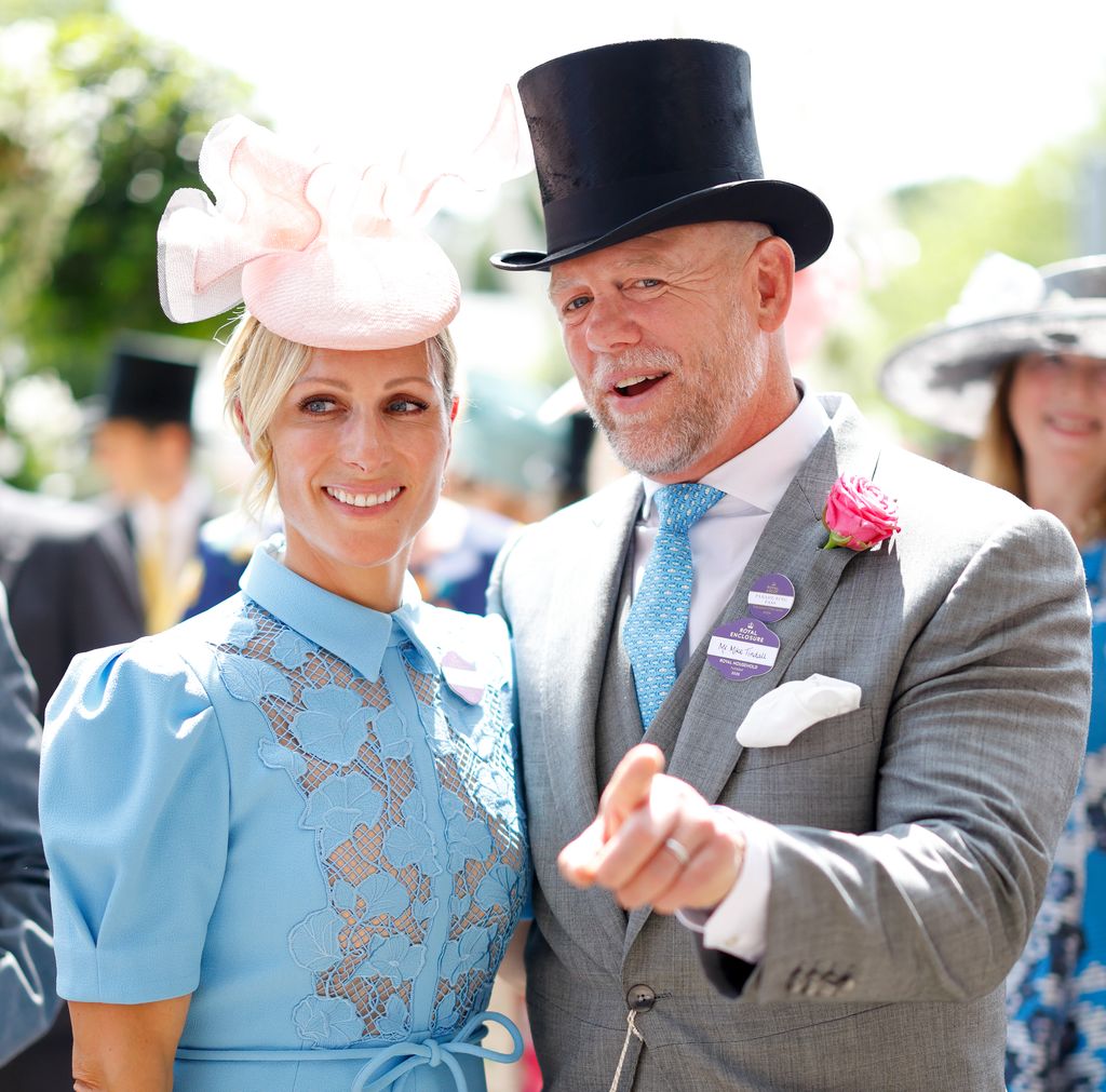 Zara Tindall smiling in blue dress and Mike Tindall in top hat pointing