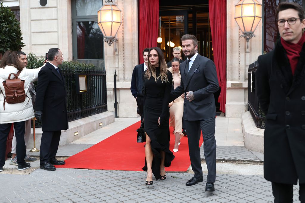 David and Victoria Beckham wear black and grey and walk out of a hotel - followed by their children