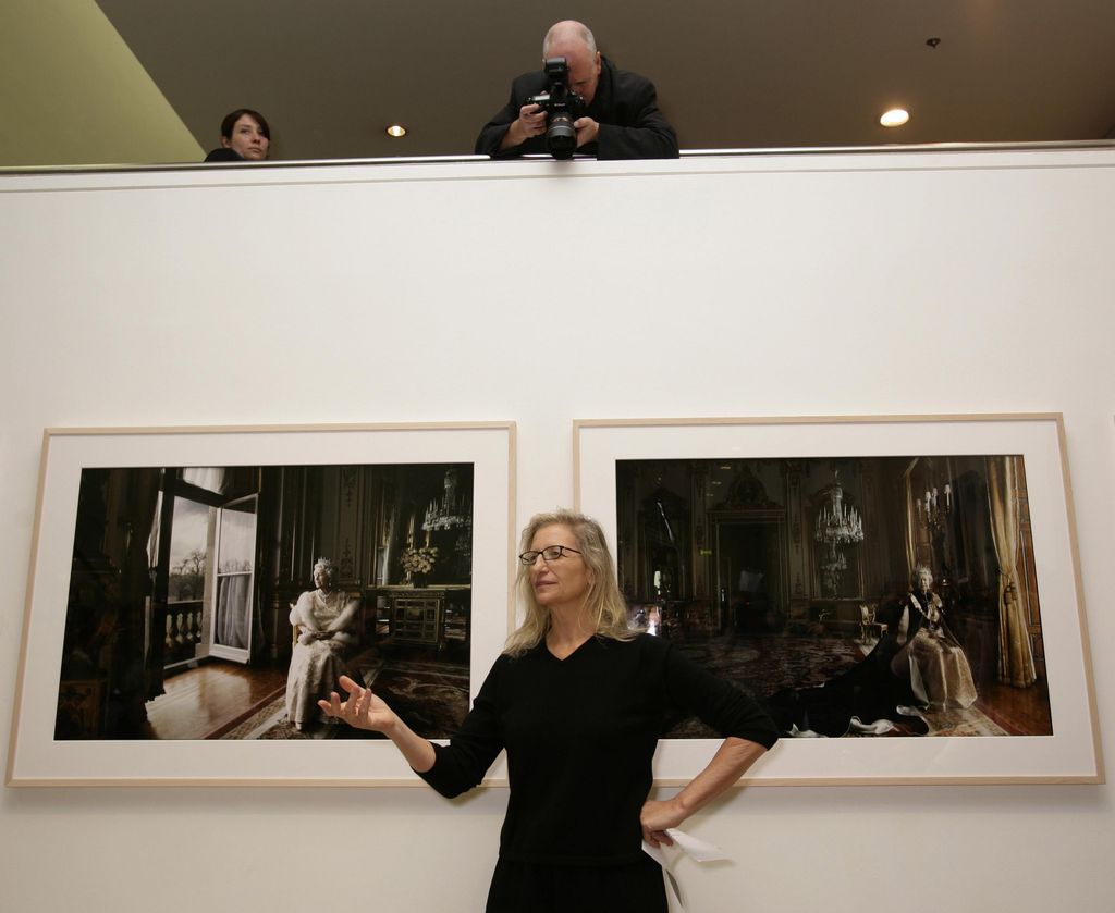 Annie Leibovitz standing in front of two of her famous portraits of Queen Elizabeth II at the National Portrait Gallery in London