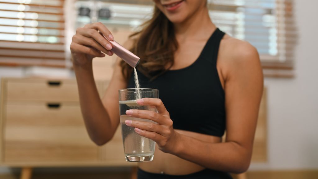 woman adding collagen powder to a drink