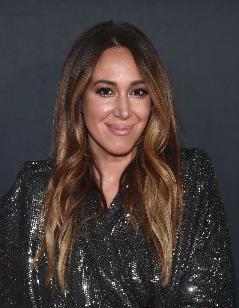 Haylie Duff wears a black sparkly dress and smiles at the camera.