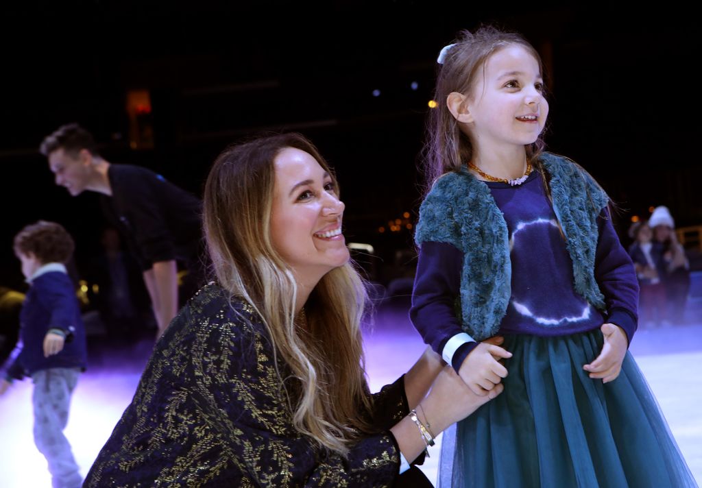 Haylie Duff crouches next to her daughter and holds her hand.