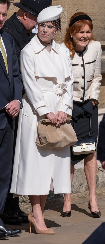 Princess Eugenie stands outside St George’s Chapel in a cream belted coat with a tan clutch and netted hat, joined by Sarah Ferguson in a boucle jacket and headband.