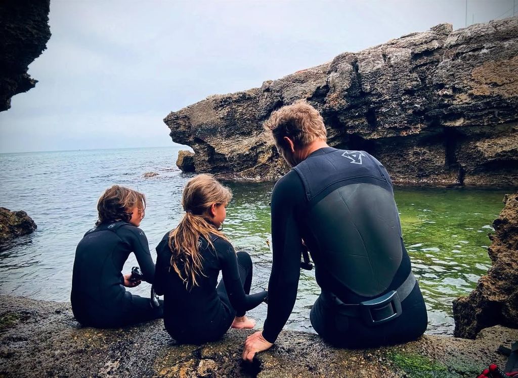 David Paul Olson in wetsuit sits with his two children