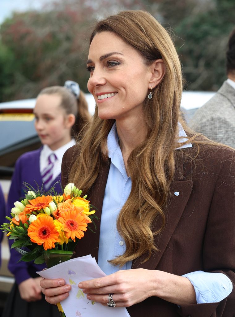 Kate Middleton walking with a bouquet of flowers