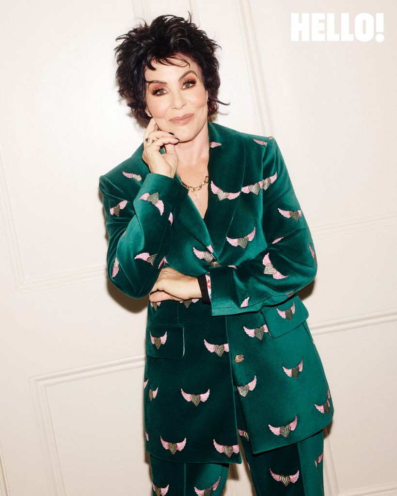 A brunette woman in a colourful green suit looks at the camera