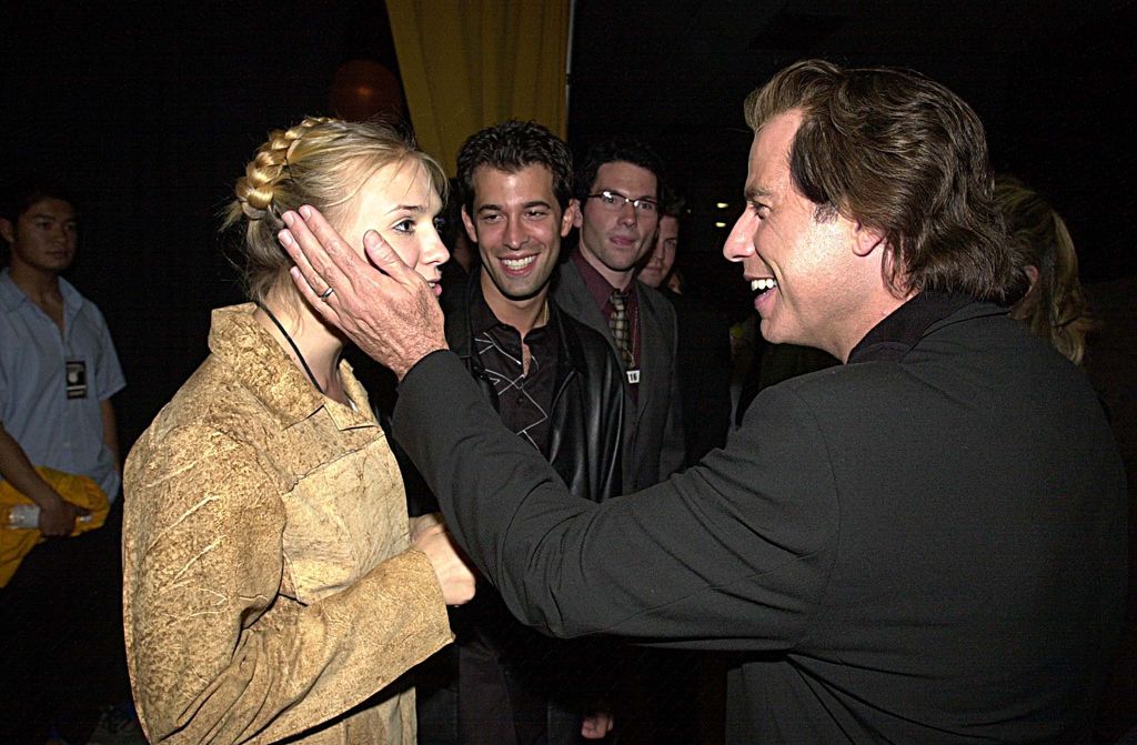 John Travolta holds one hand on the side of Dominique Swain's face as they talk to each other.