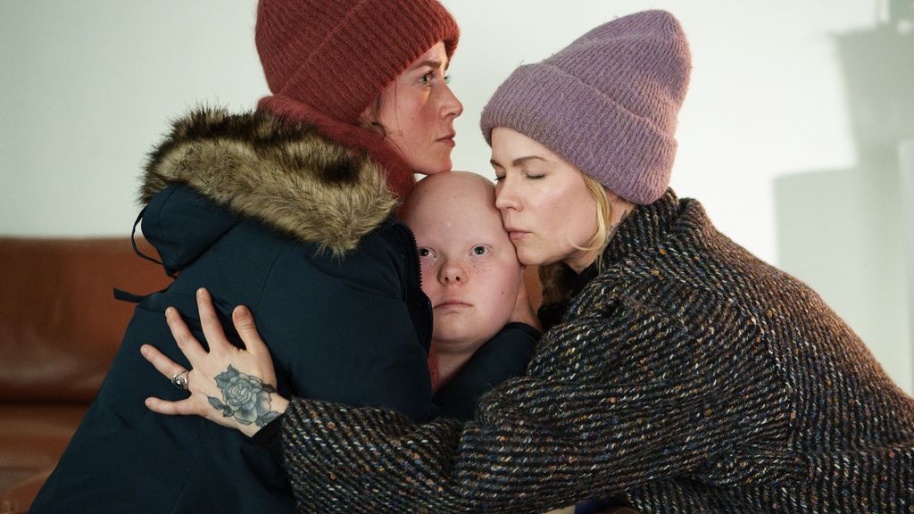 two women hugging child