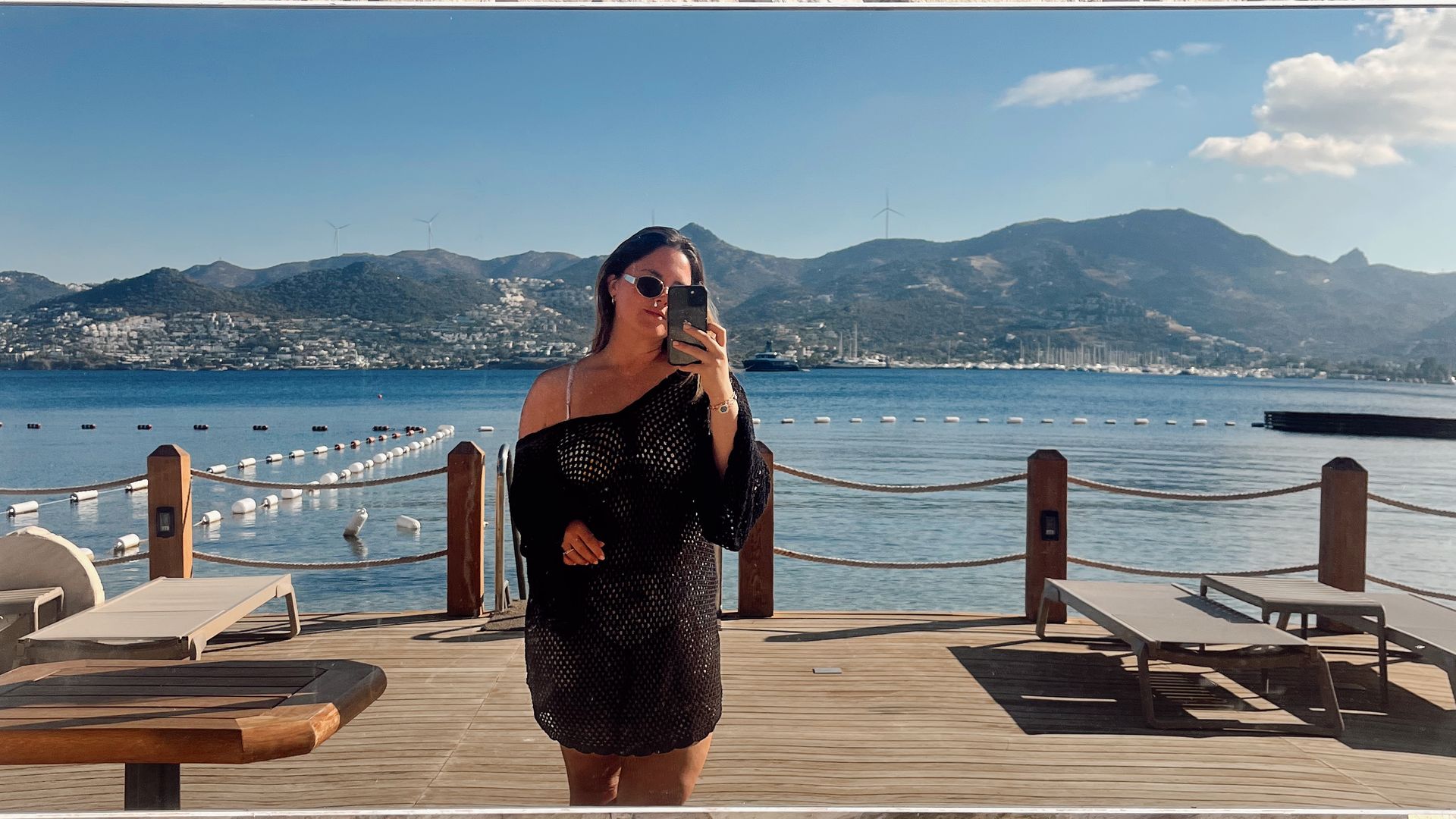 Guest taking a mirror selfie on the seafront deck at Avantgarde Refined Bodrum, with views across the bay and mountains in Yalıkavak.