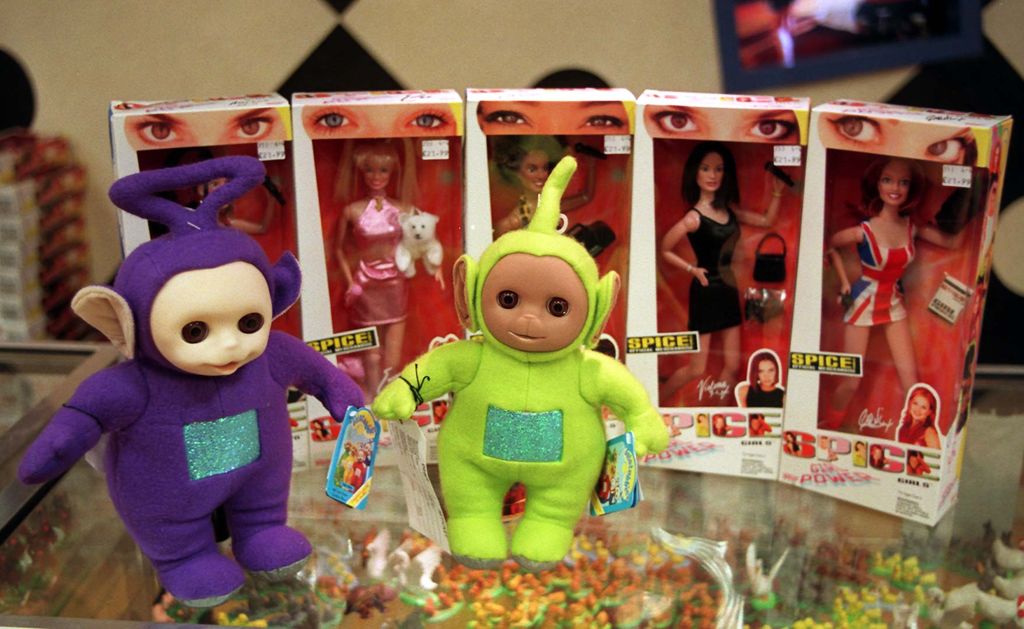 Teletubbies stand in front of Spice Girls dolls in boxes.
