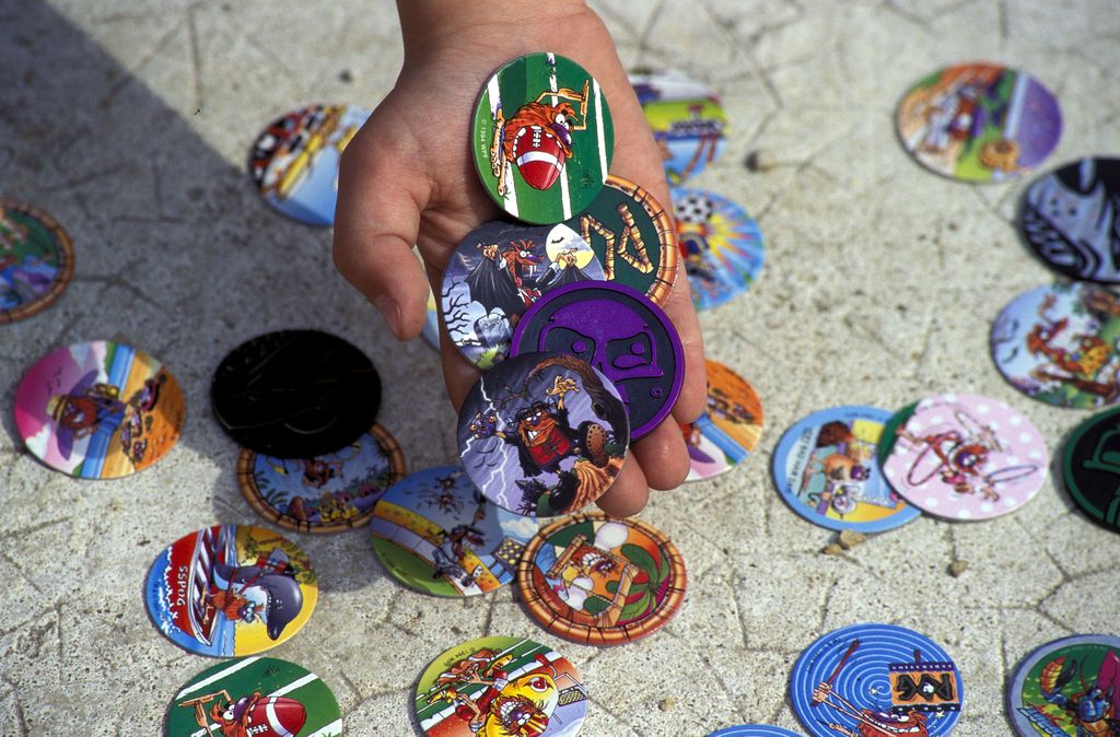 Child holds a handful of small colourful disks.