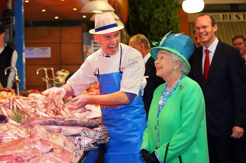  Queen Elizabeth standing with fishmonger at counter