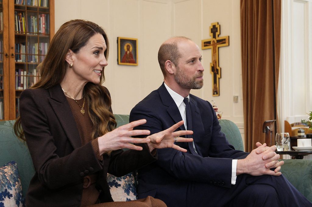 Prince William and Princess Kate looking serious sitting on a sofa