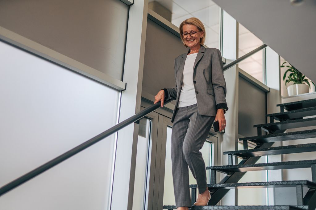 woman wearing grey suit walking down stairs in office