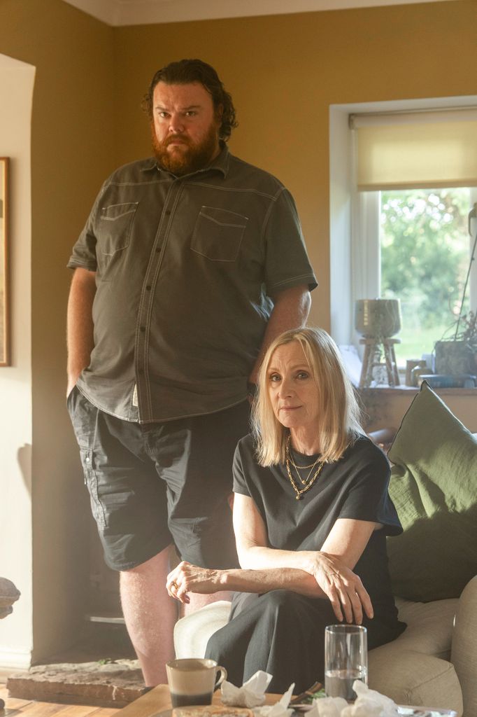man standing next to woman sitting on sofa in house