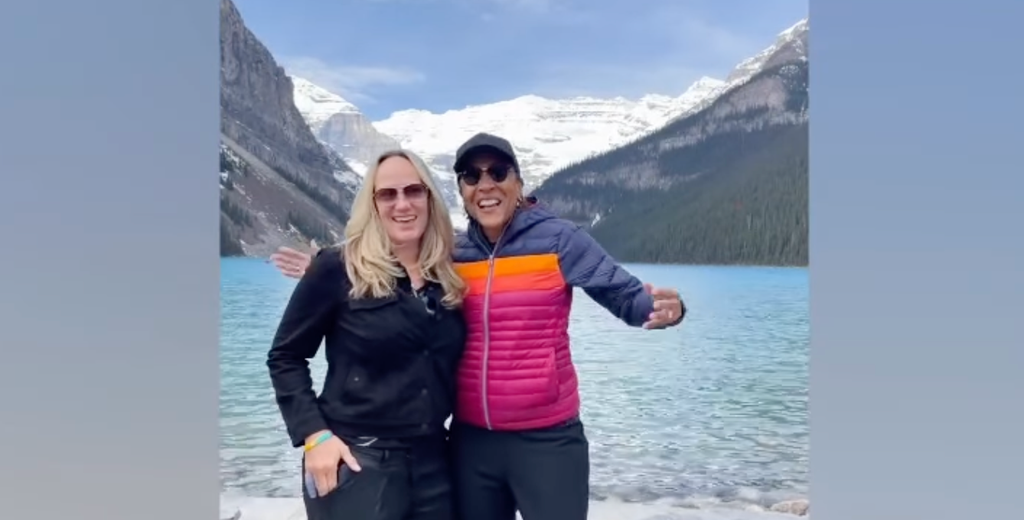 Robin and Amber posing in front of mountains and a lake