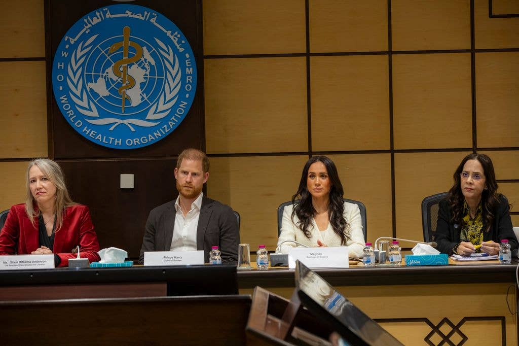 Prince Harry with a stern face sitting at a roundtable