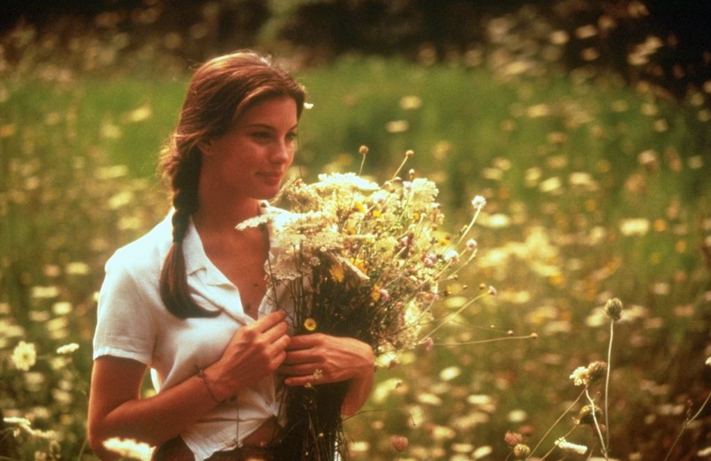 Liv Tyler in Stealing Beauty, carrying a bouquet of flowers in a field.