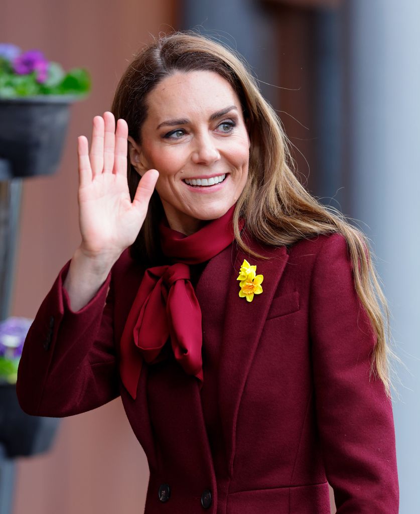 Catherine, Princess of Waleswaving in burgundy dress and coat