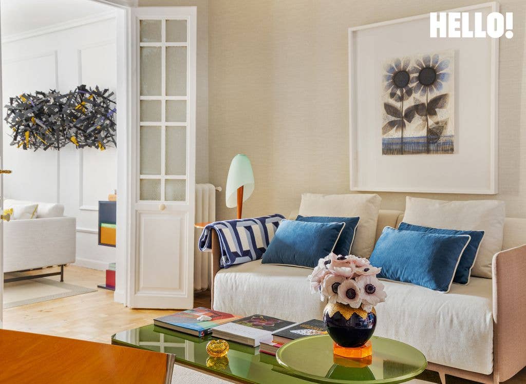 One of the living rooms features a white sofa with blue cushions, an orange carpet, and a lime-green glass coffee table, with art on the wall and white panelled doors leading into another room inside designer Silvia Tcherassi's Madrid home 