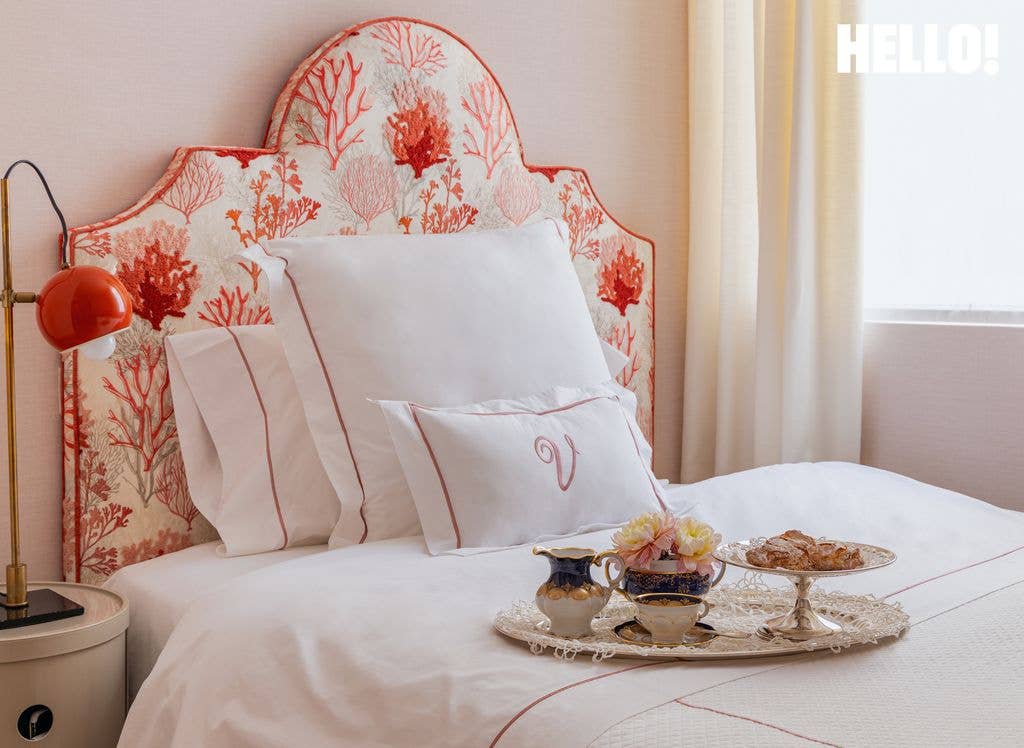 A headboard upholstered with a coral motif and white bedsheets, featuring a tray on the bed, in one of the bedrooms inside designer Silvia Tcherassi's madrid home 