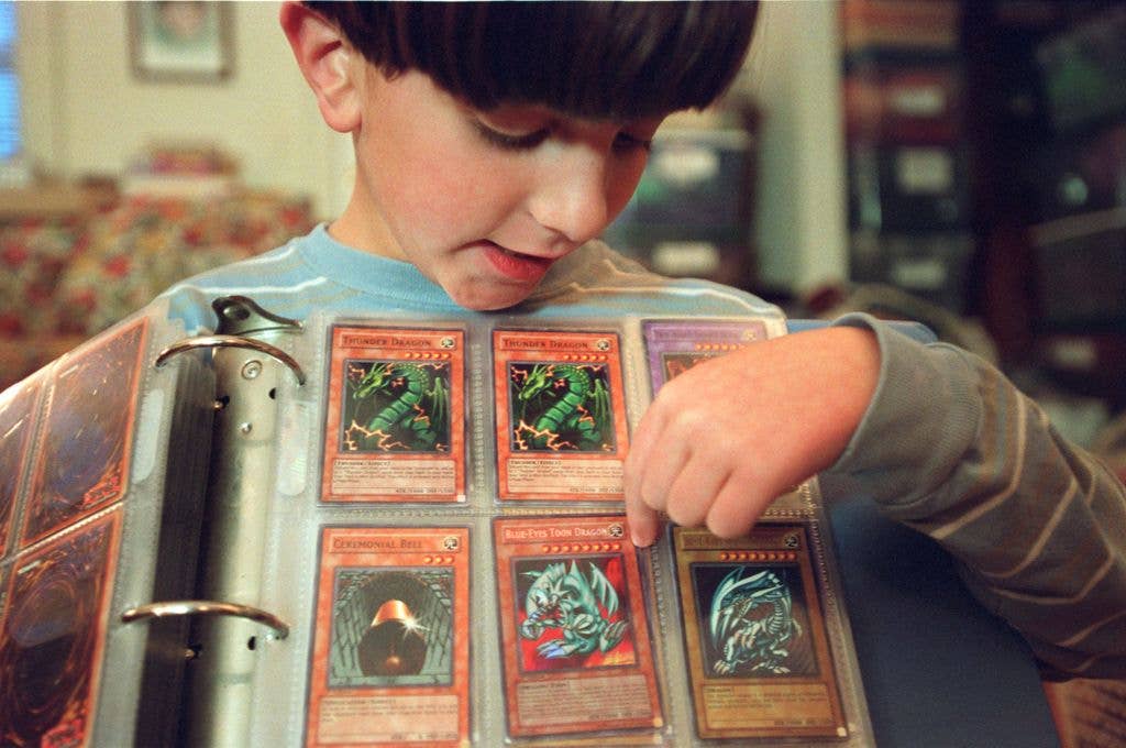 A young boy shows his collection of Yu Gi Oh! cards in a hinged folder of plastic wallets.